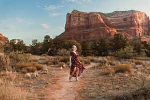 A hiker on a desert trail admires the majestic red rock formations of Sedona at sunset.