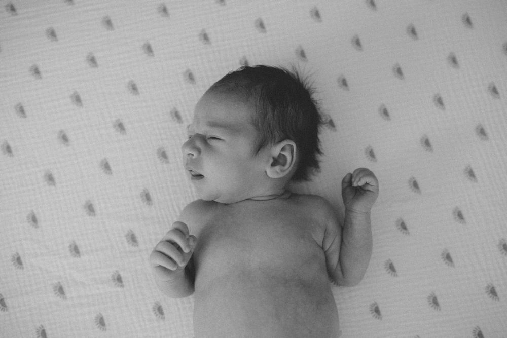 A sleeping newborn baby lies peacefully on patterned bedding in black and white in suffolk, virginia home
