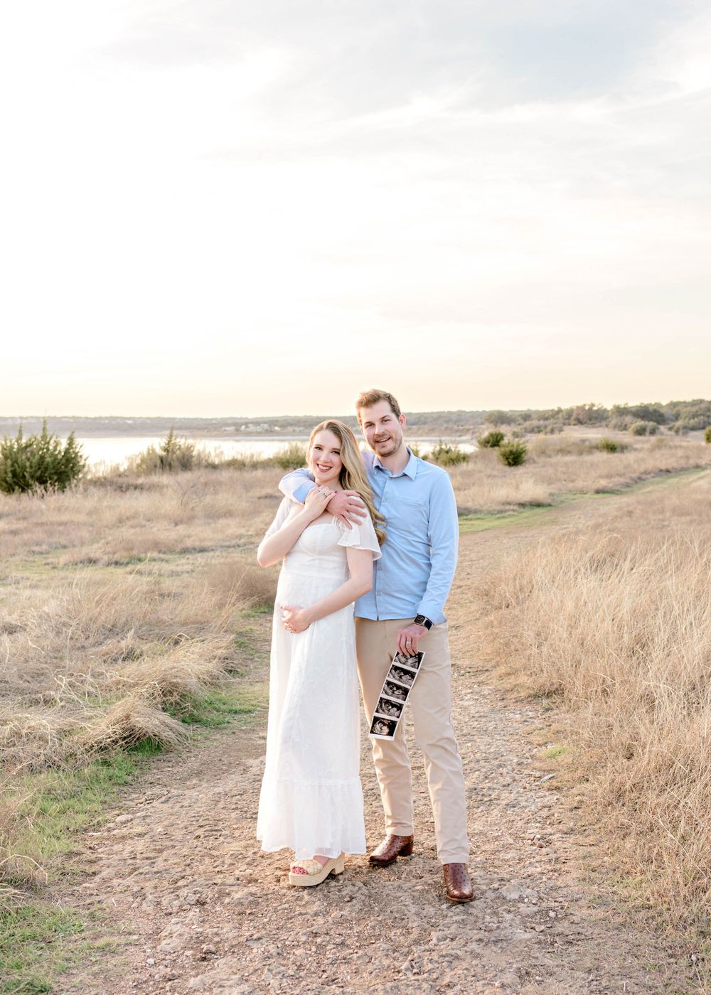A couple shares tender moments along a scenic coastal trail during golden hour.