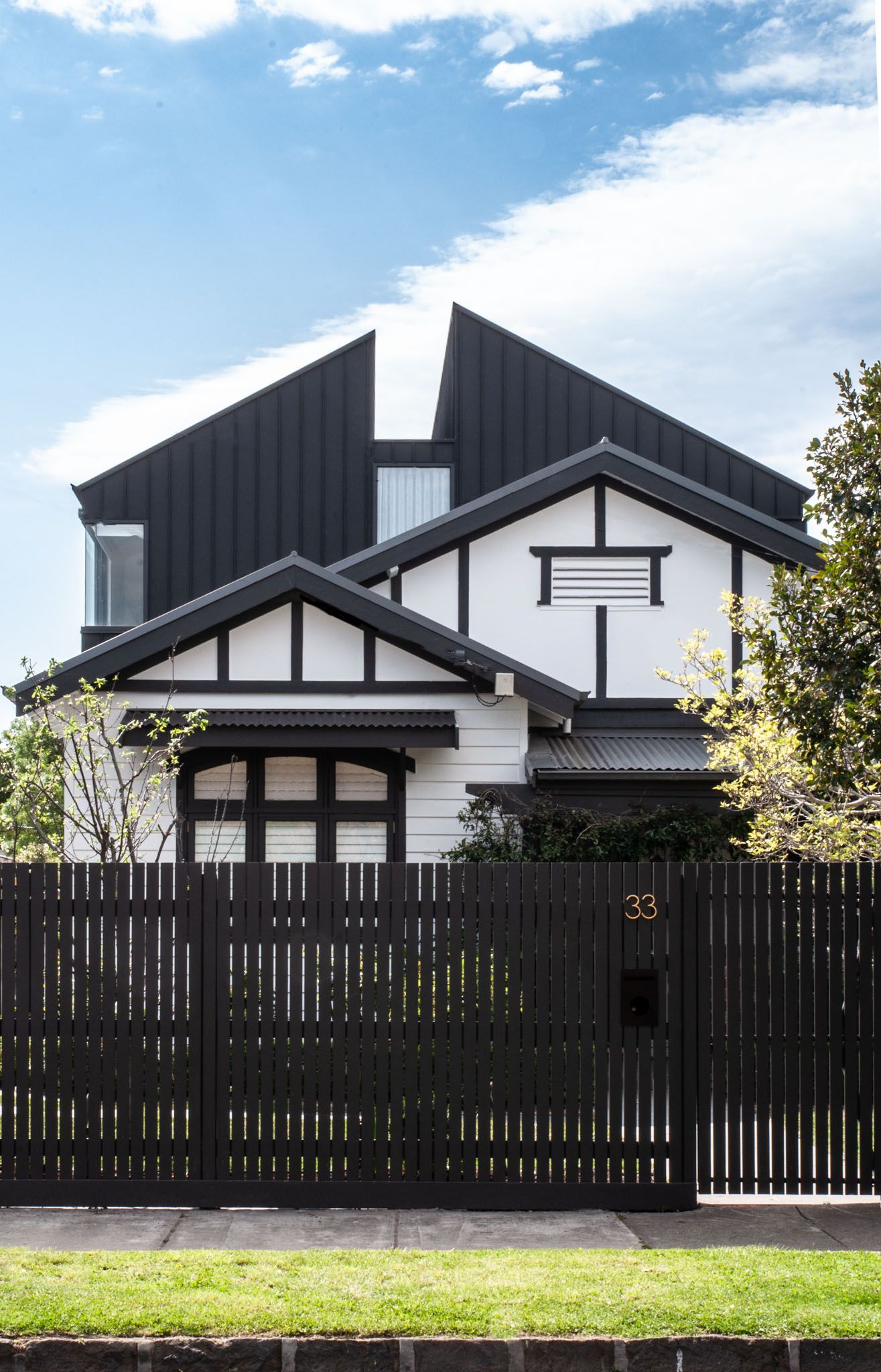 Modern two-story house with black and white exterior featuring Japanese-inspired architecture and dark wooden fence.