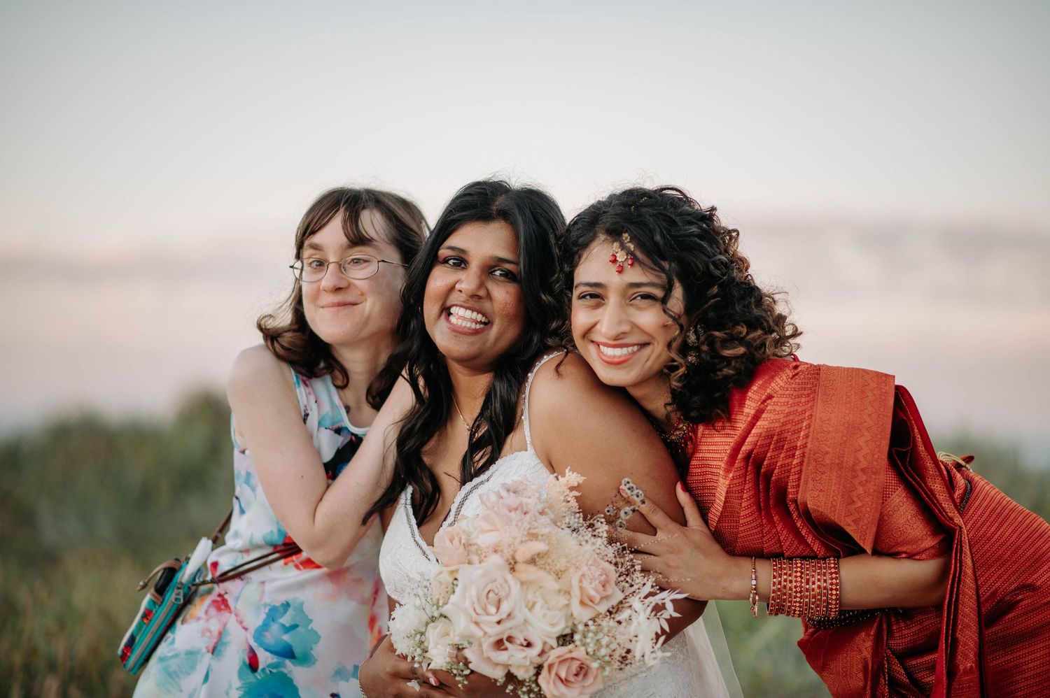 Three friends share joyful laughter together outdoors at sunset.