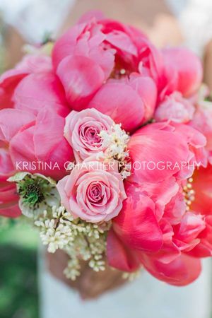 Close-up of pink peonies and roses bouquet with delicate white baby's breath accents.