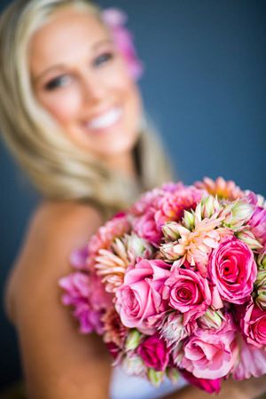 Vibrant pink and coral rose bridal bouquet in focus with blurred background.