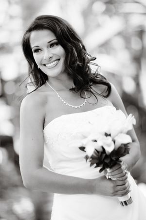 Black and white bridal portrait showing joyful expression and floral bouquet.