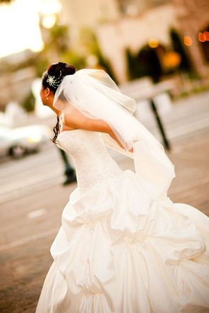 A bride in a flowing white wedding dress twirls dramatically at sunset.