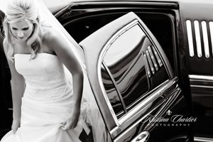 Black and white photo of a bride in strapless gown stepping out of a luxury car.