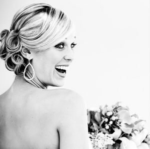 Black and white portrait of joyful bride with elegant updo hairstyle.