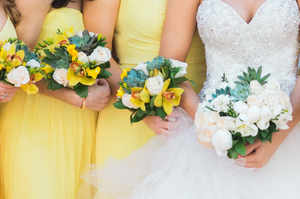 Wedding party detail showing yellow bridesmaid dresses and mixed floral bouquets.