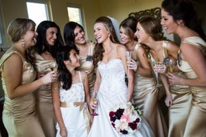 Bridesmaids in champagne-colored dresses gather around the bride in a candid moment.