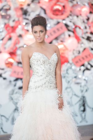 A glamorous strapless wedding dress with crystal embellishments and feathered tulle skirt against a floral backdrop.