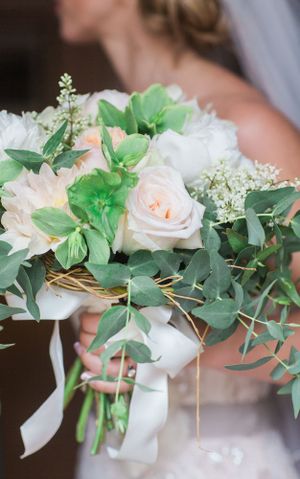 Elegant bridal bouquet featuring blush roses, white flowers, and cascading greenery tied with ribbon.