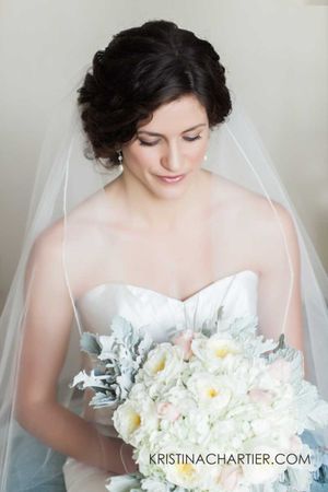 Classic bridal portrait showcasing a white strapless gown and delicate bouquet.