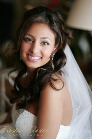 Joyful bridal portrait featuring soft curled hair, veil and strapless gown.
