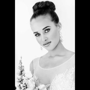 Black and white bridal portrait showing elegant updo hairstyle and delicate lace wedding dress details.