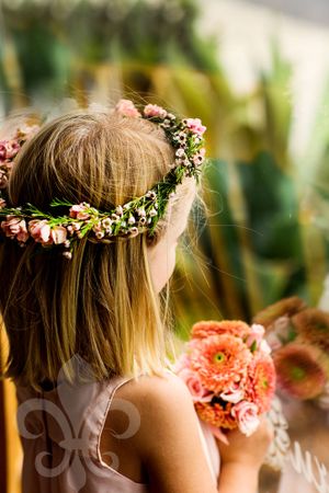 Young attendant wearing floral crown of pink flowers and delicate blooms.