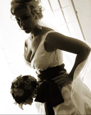 Artistic black and white photo of bride in vintage-styled dress with bouquet.