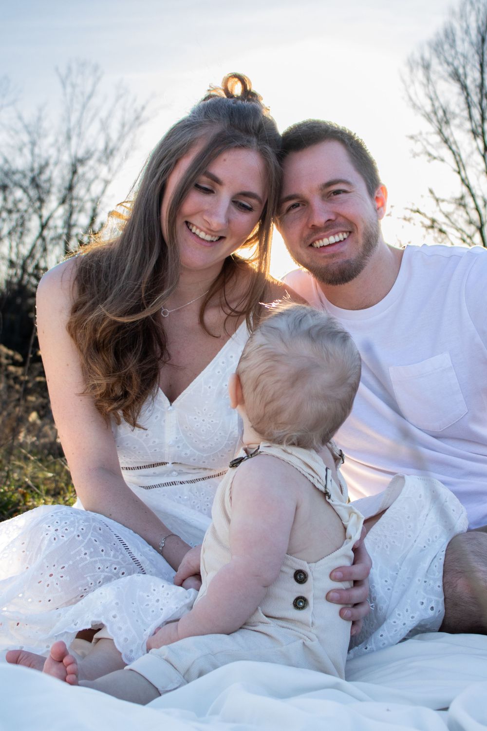 mom and dad smiling at baby looking up at them