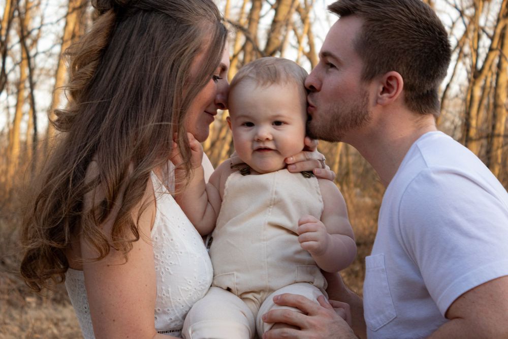 mom and dad kissing baby
