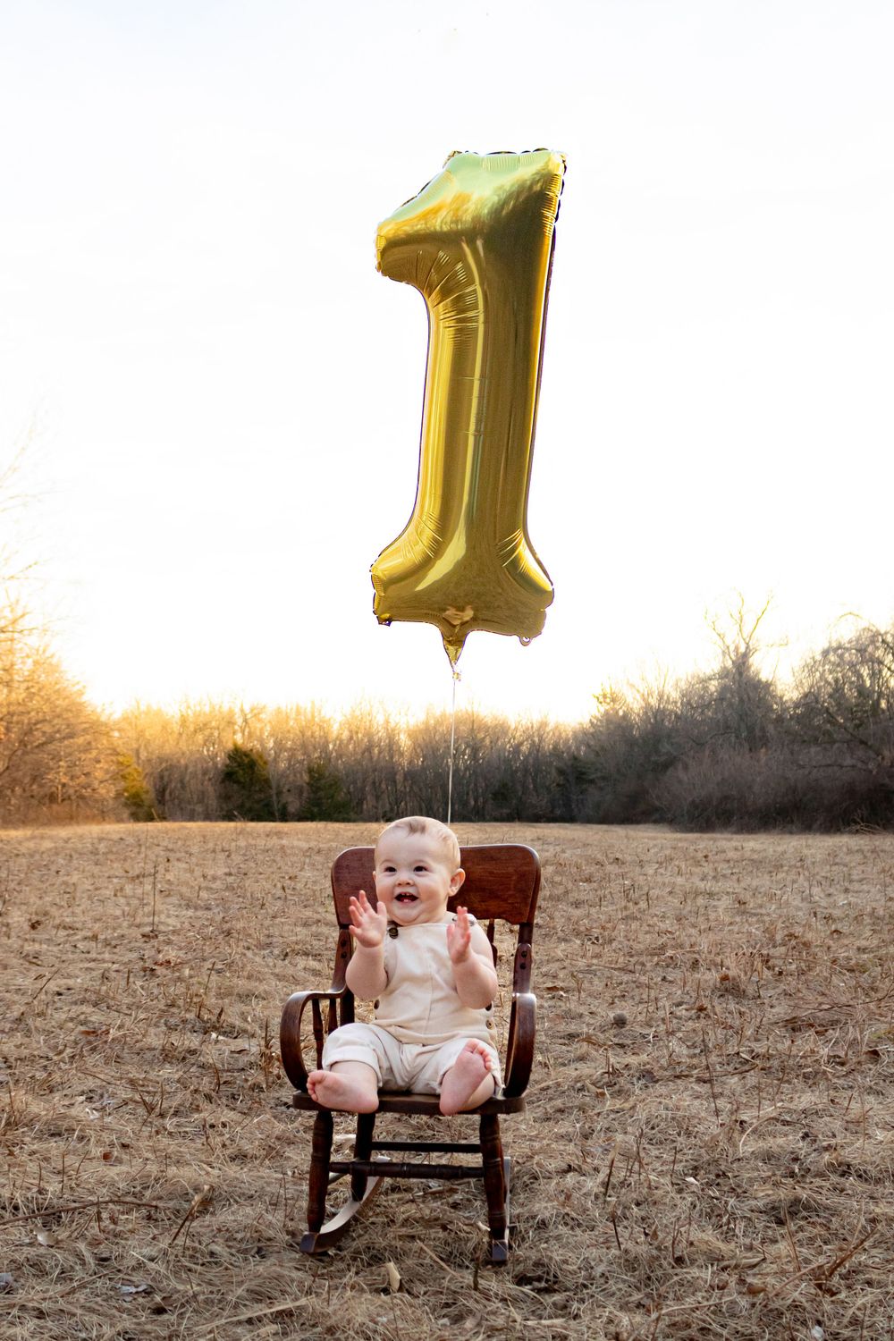 baby in rocking chair with number 1 balloon above him