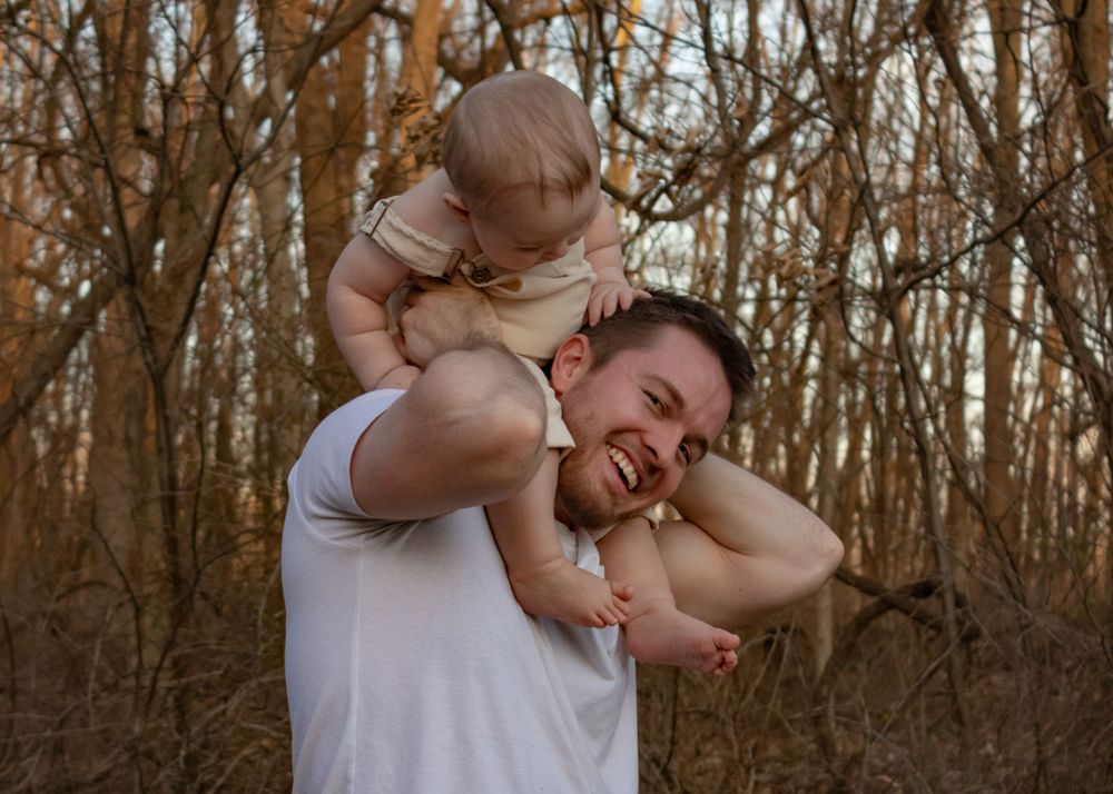baby on dads shoulders looking down at him