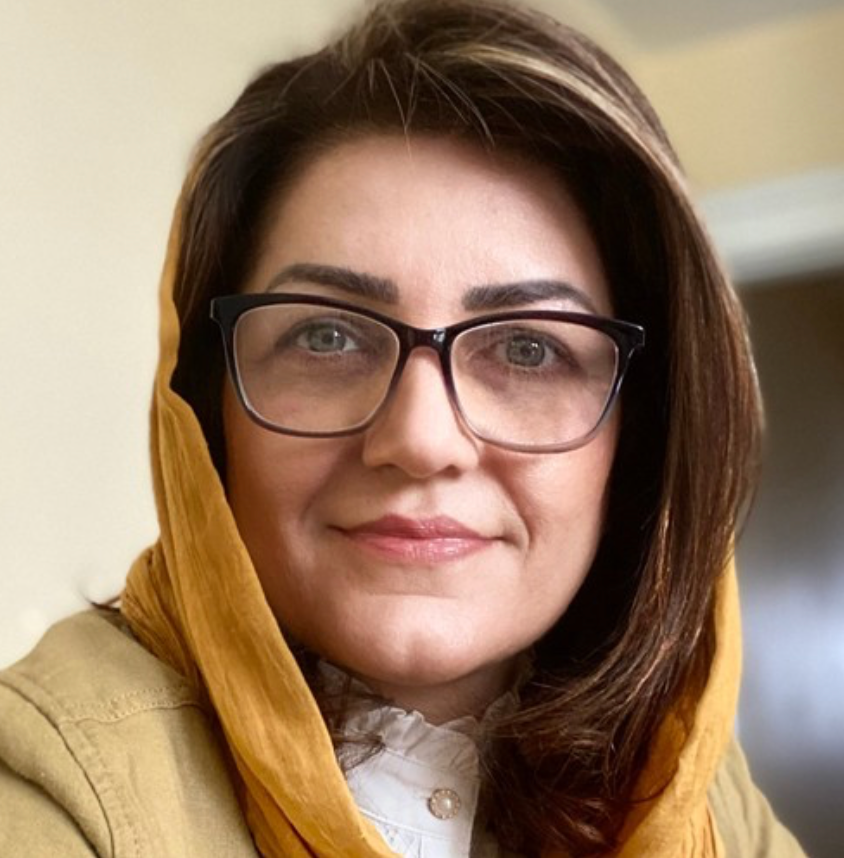 Woman wearing glasses and yellow hijab smiling warmly in a close-up portrait photo. Embracing Life’s Beauty
