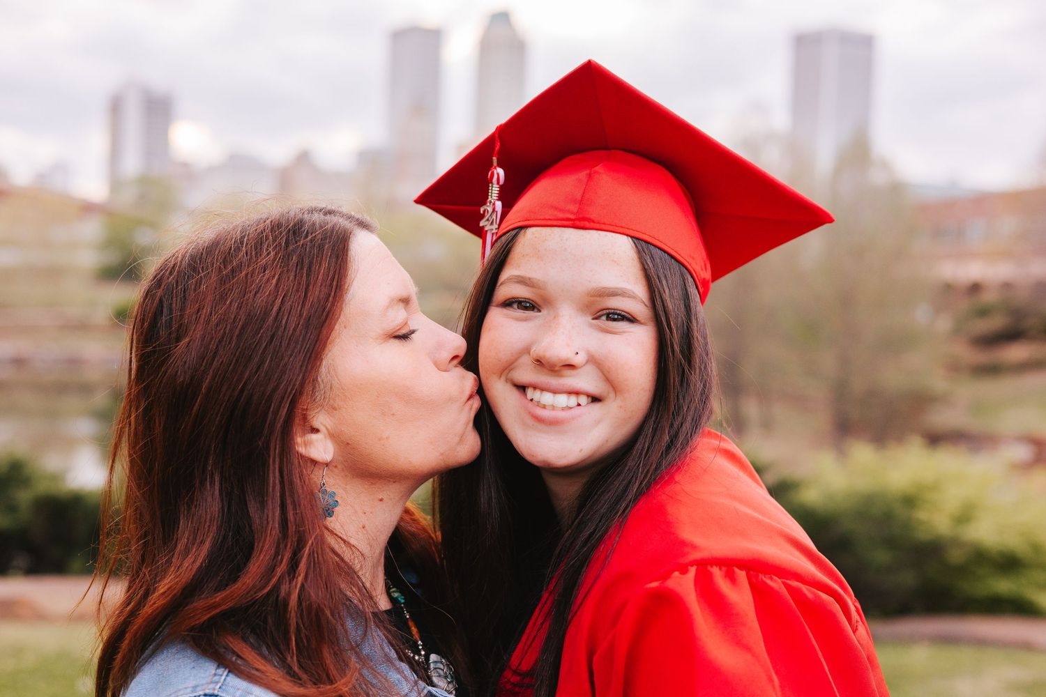 Graduation celebration photoshoot with red cap against city skyline backdrop.