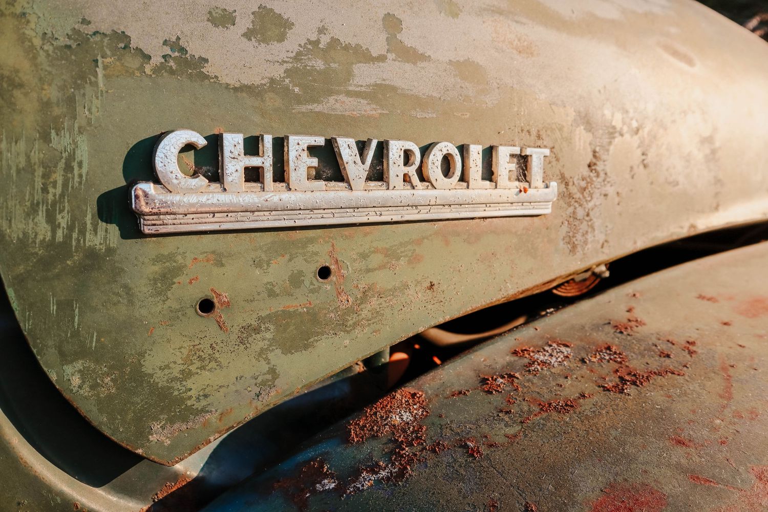 A weathered vintage Chevrolet emblem on faded metal shows the patina of time.