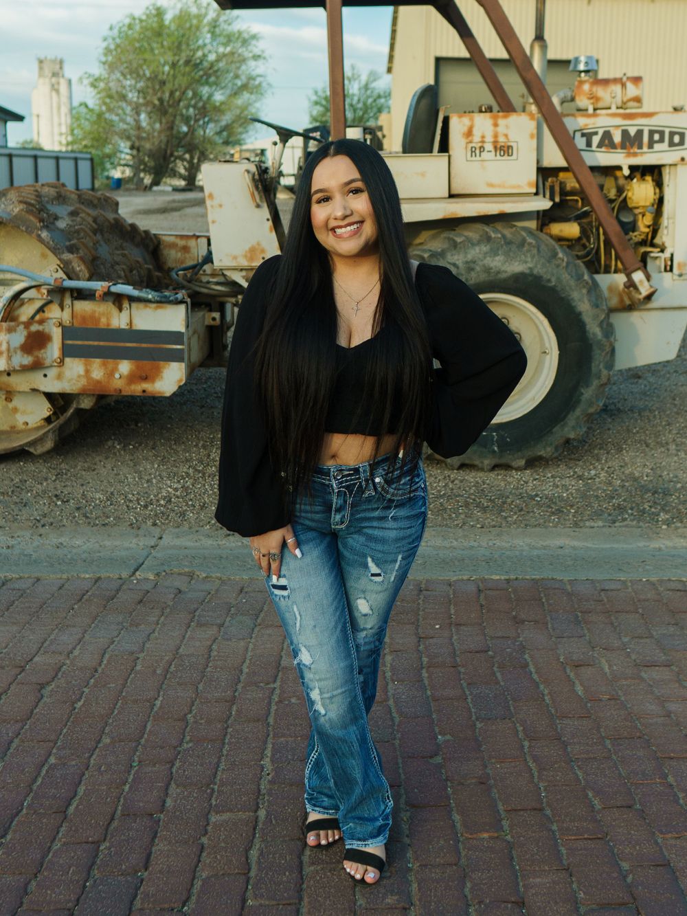 Urban fashion shoot featuring casual streetwear with vintage farm equipment in background.