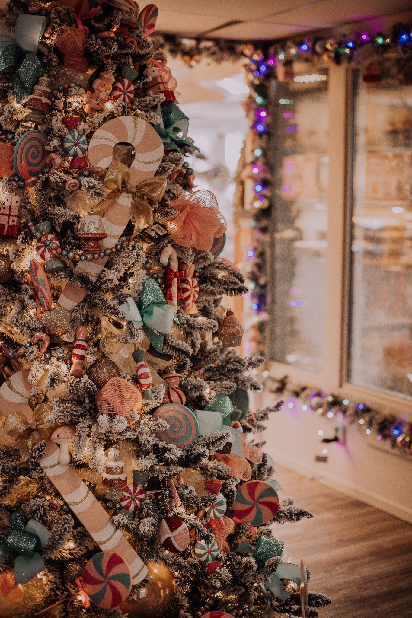 Beautifully decorated Christmas tree with pink and white ornaments glowing in warm indoor lighting.