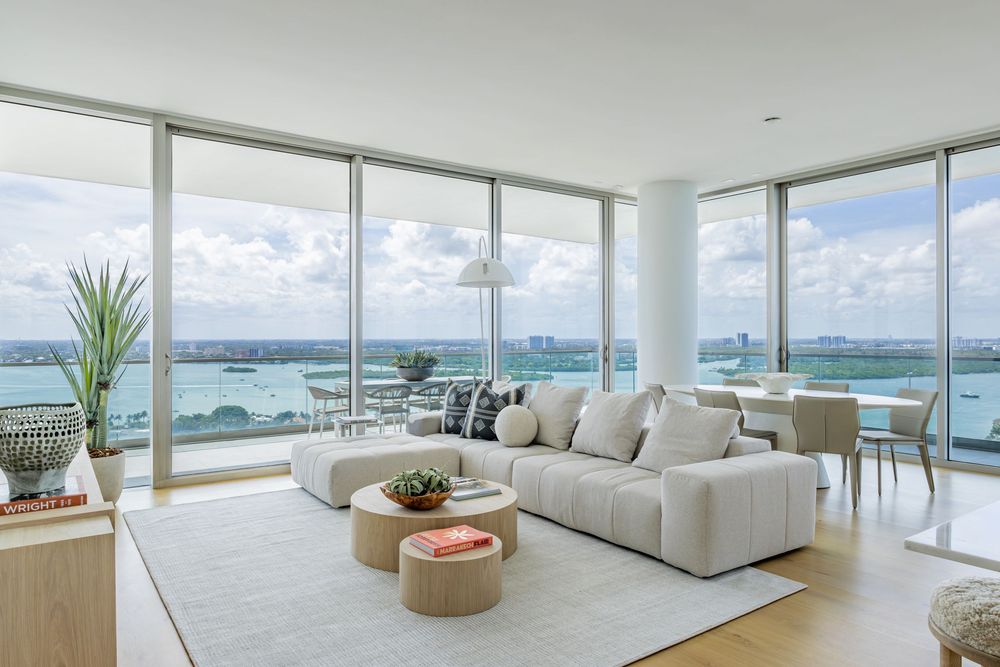 Expansive oceanfront living room with white sofas and panoramic views of the coastline.