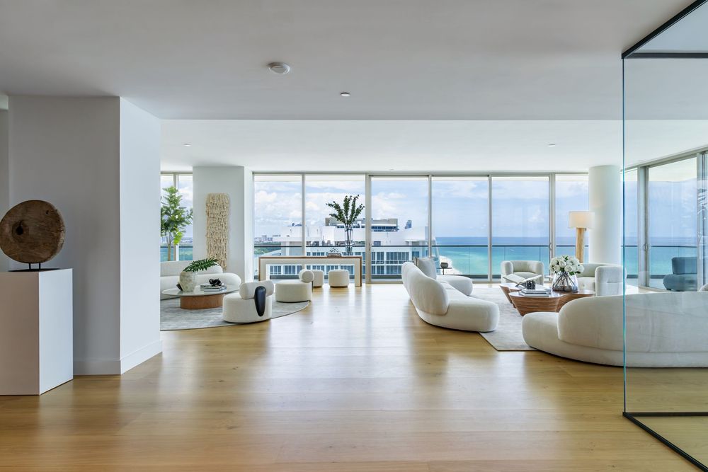Stunning panoramic view of a modern white penthouse interior with floor-to-ceiling windows and ocean vistas.
