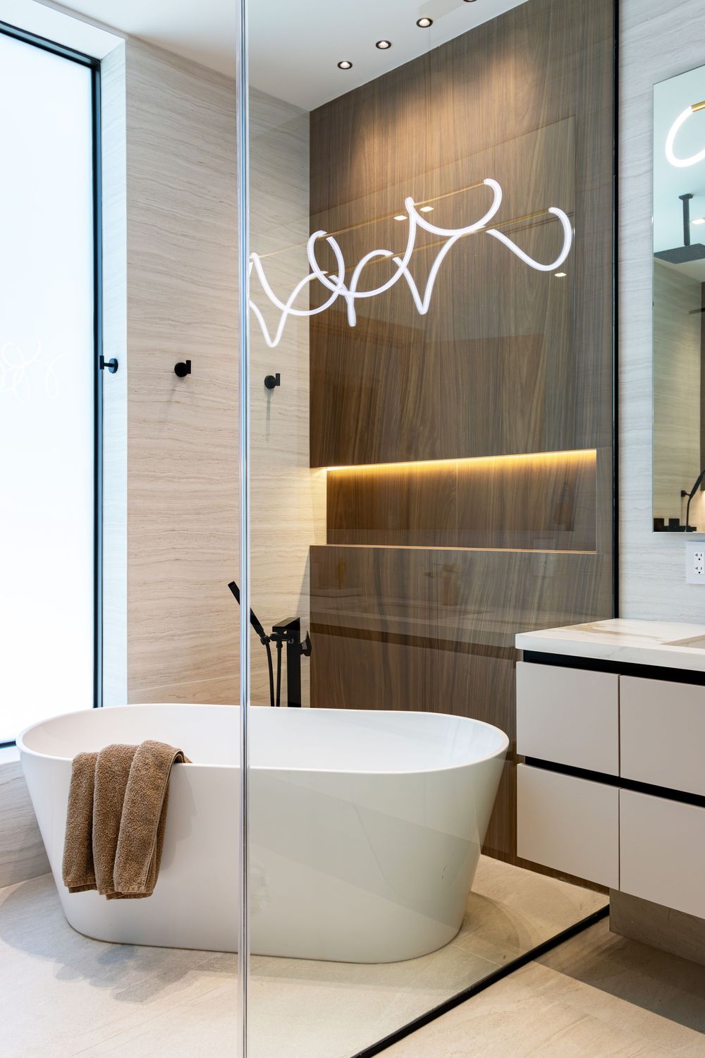 Contemporary bathroom featuring a freestanding white tub, glass shower enclosure, and warm wood accent walls.