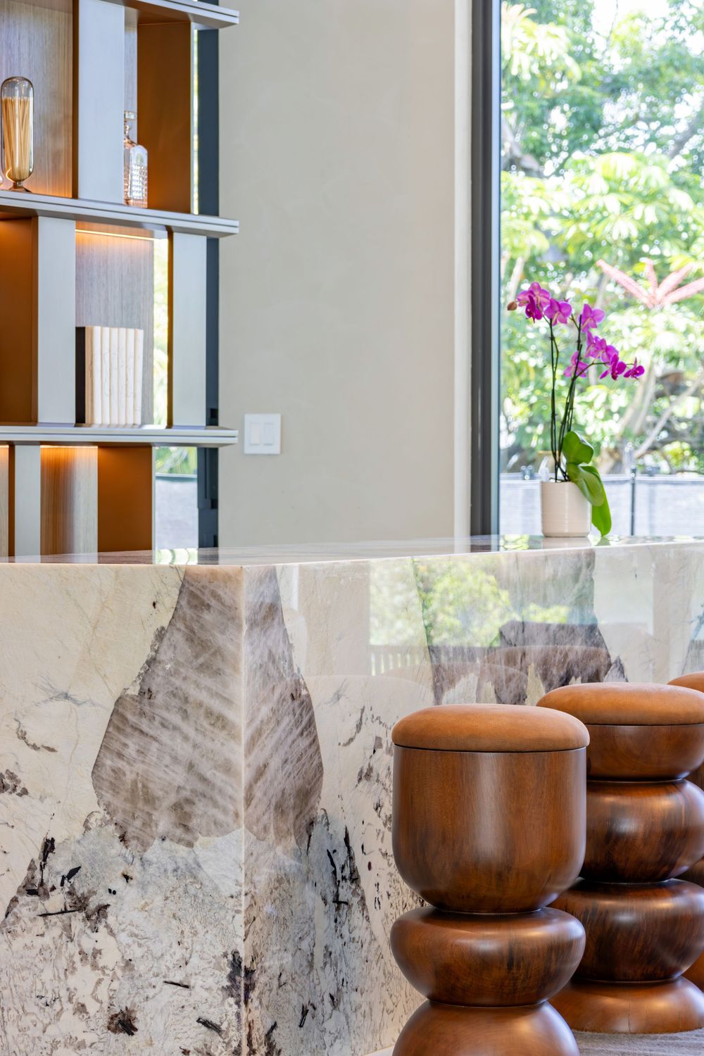Elegant sitting area with decorative wooden stools and marble wall details near large windows.