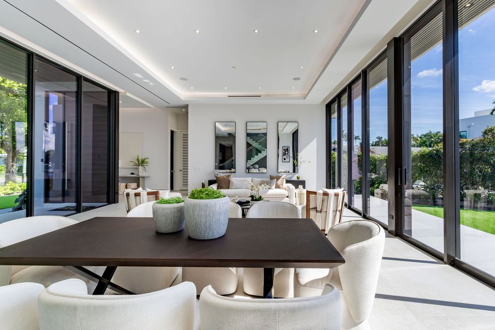 Modern white living space with floor-to-ceiling windows and contemporary furnishings bathed in natural light.