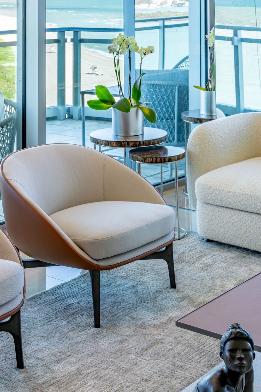 Luxurious waterfront lounge area with plush white chairs and ocean views through floor-to-ceiling windows.