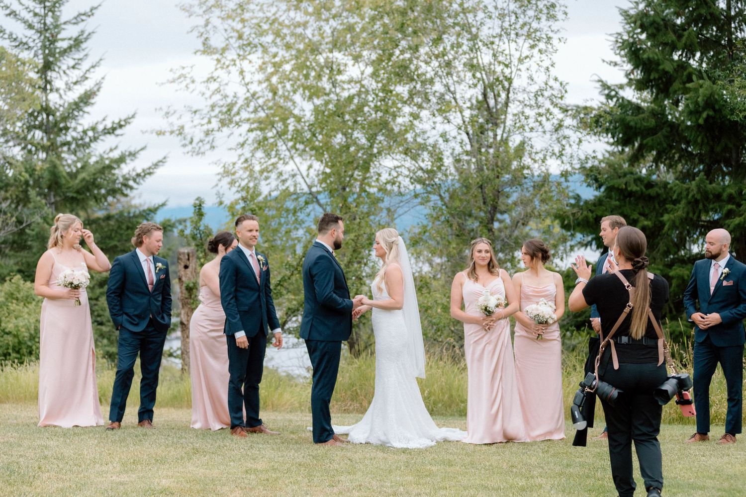 Hands on wedding photographer helping support bride in all matters. Outdoor wedding with mountains and lake backdrop