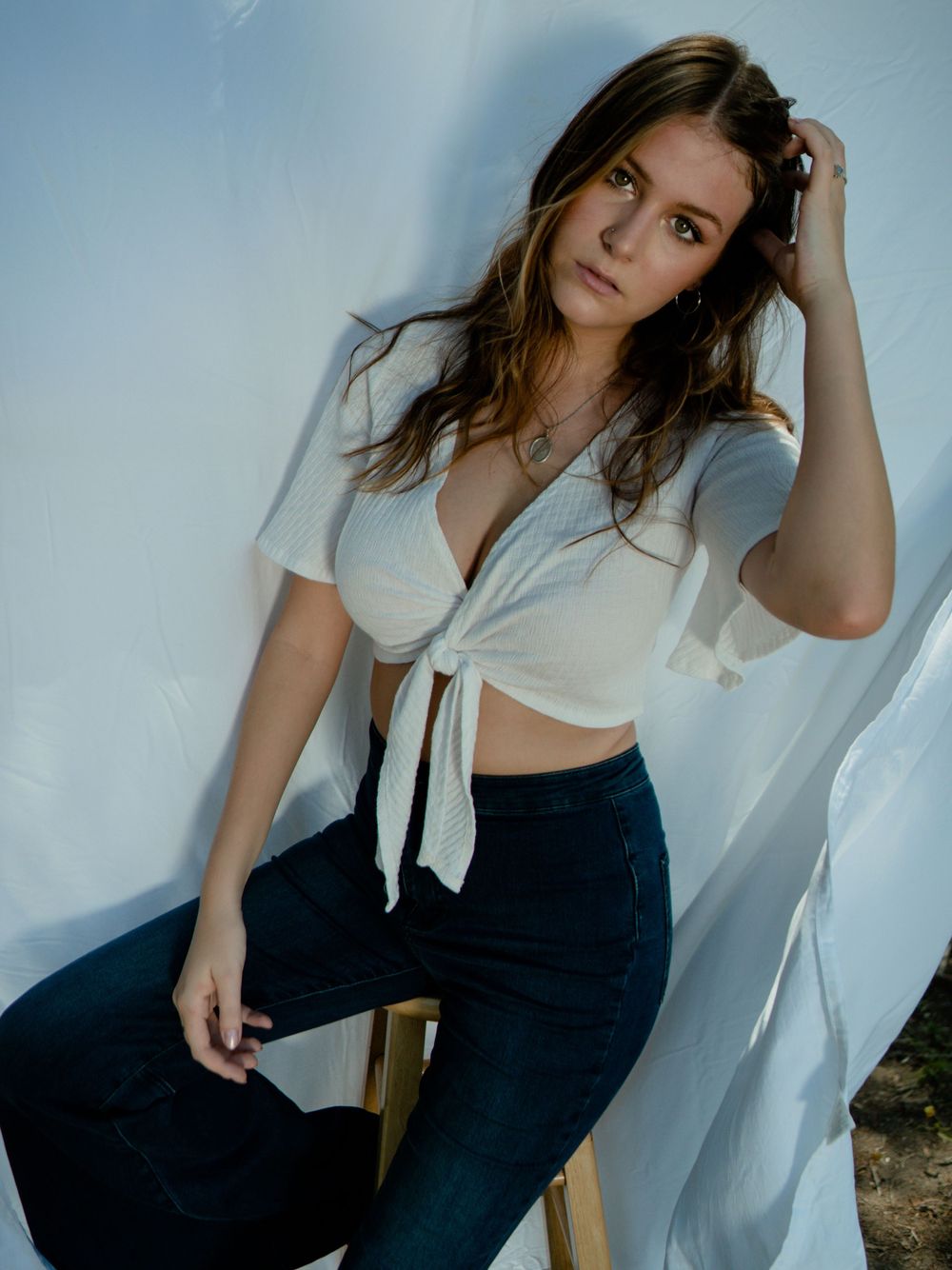 Portrait of model in white tied shirt against minimalist backdrop.