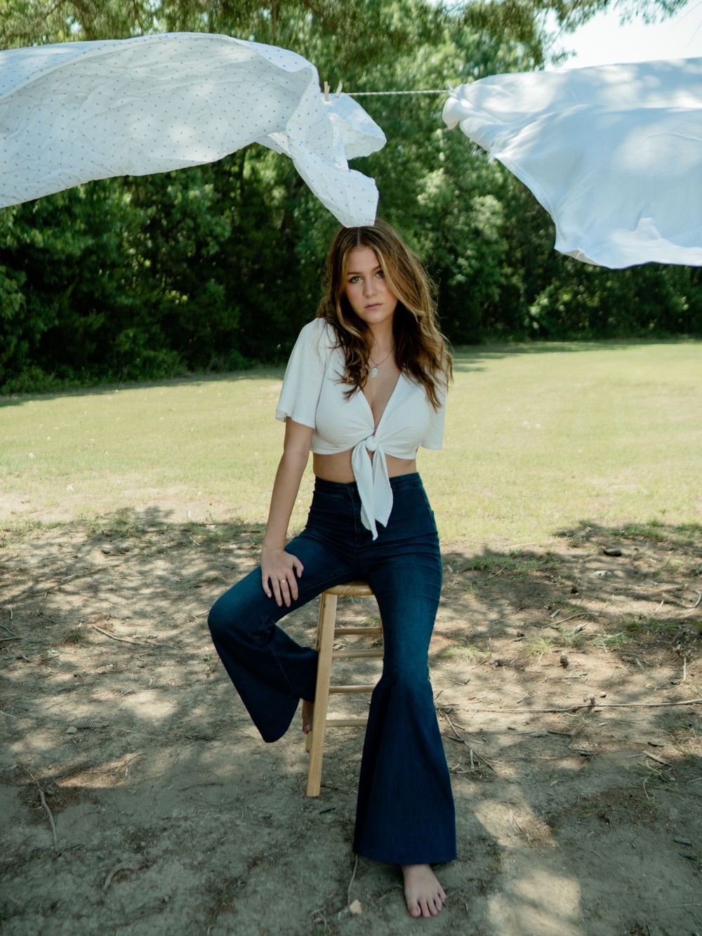 Bohemian summer style with flared jeans and cropped top in outdoor garden setting.