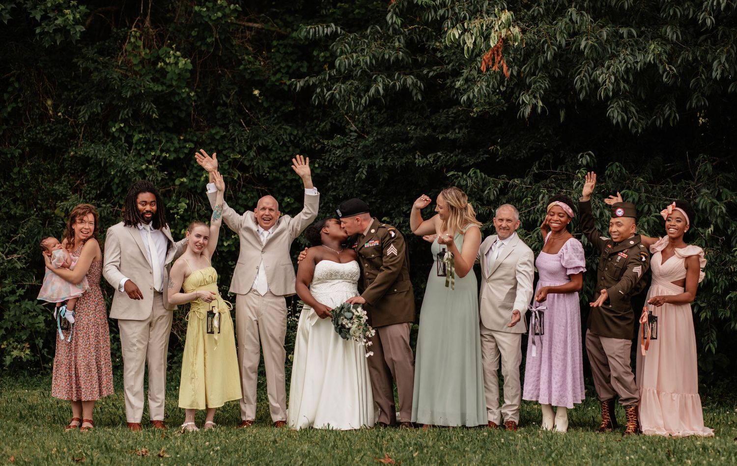 Wedding party members celebrate outdoors wearing coordinated pastel and neutral attire.