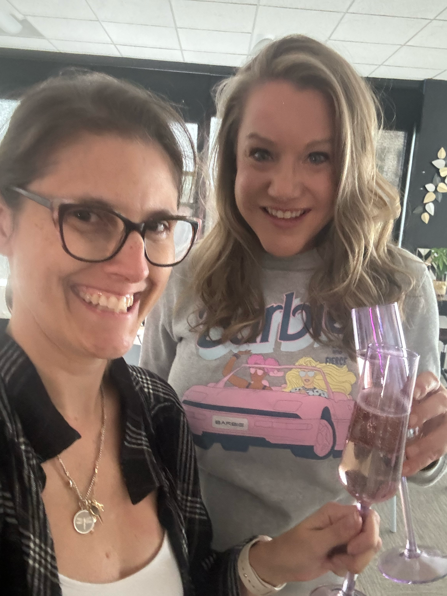 Two friends celebrating with wine glass and casual attire.