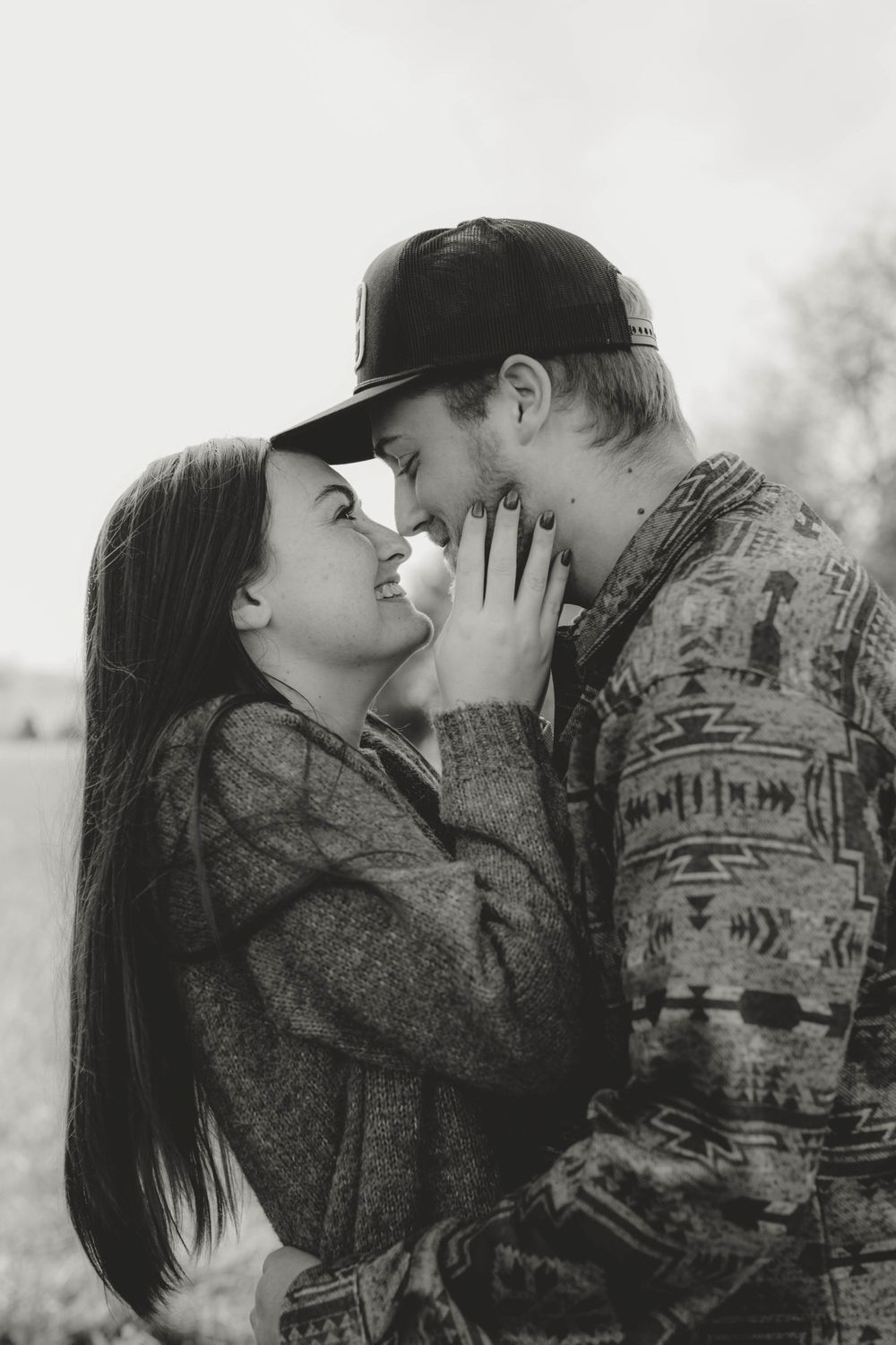 Close-up romantic portrait of couple in casual wear sharing tender moment outdoors.