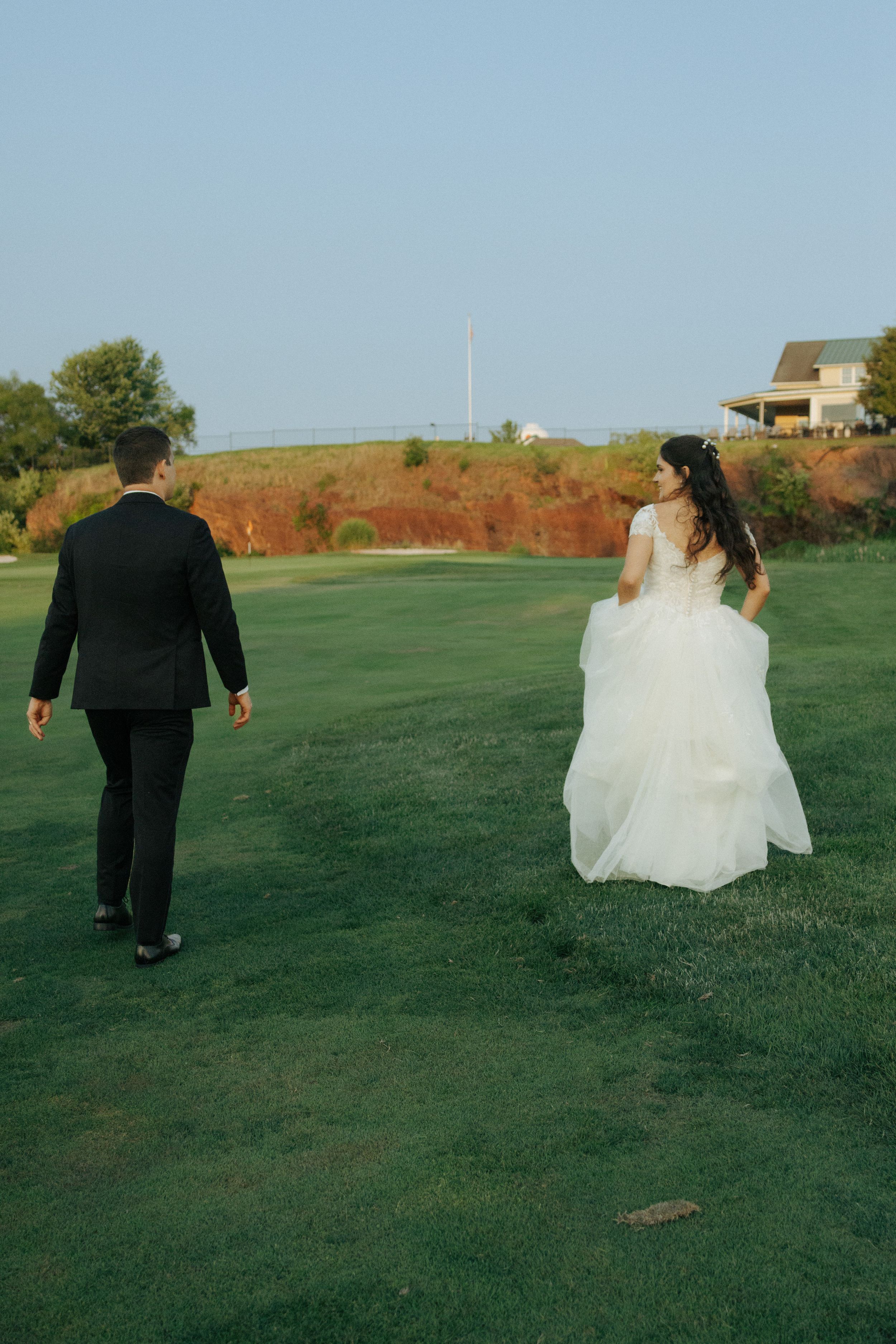 Newlyweds walking together on a scenic golf course with red cliffs in background.