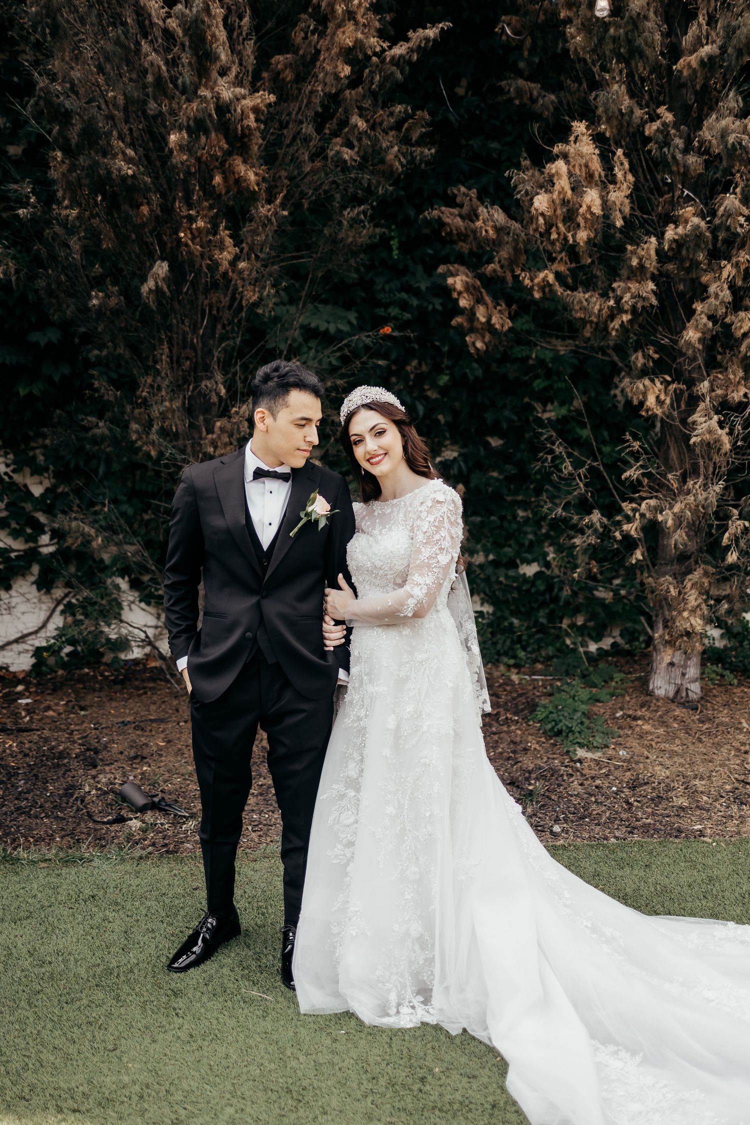 A couple shares an intimate moment in formal attire against an autumn backdrop.
