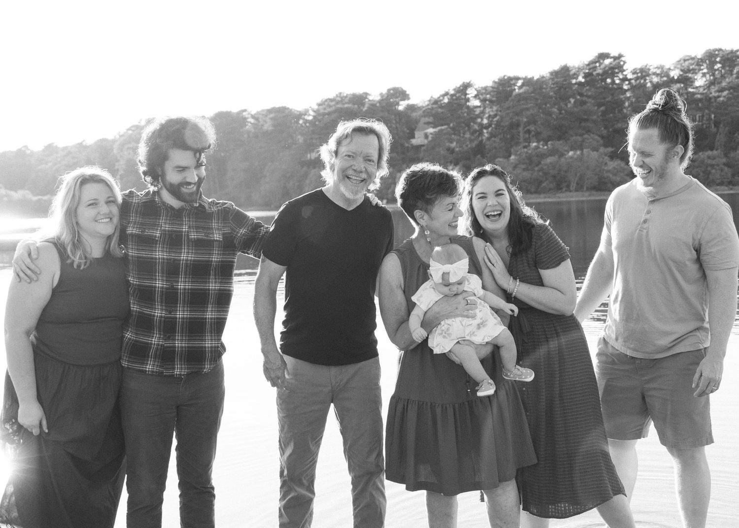 Three-generation family session on Cape Cod lake, grandparents, parents, and kids smiling together at sunset.