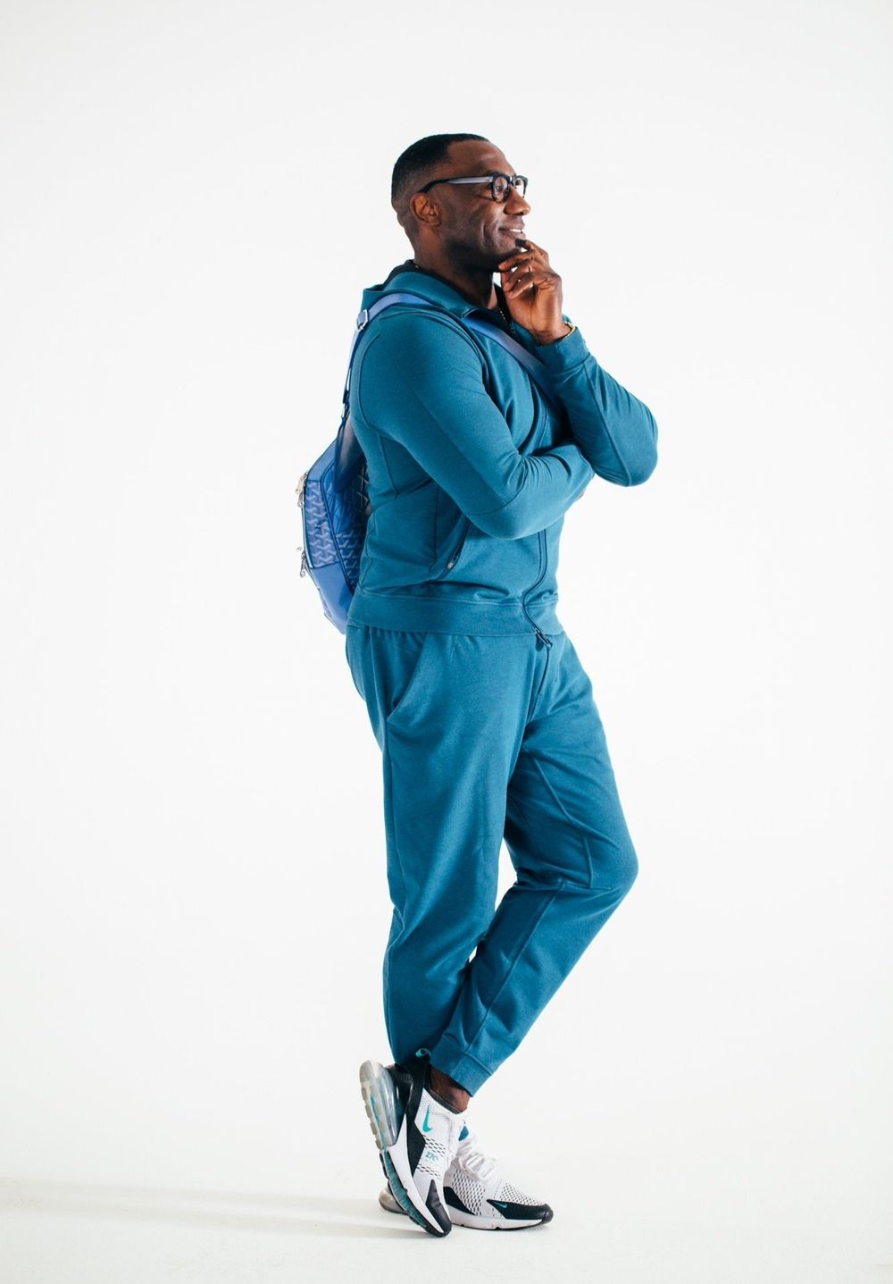 Shannon Sharpe on white backdrop in blue track suit