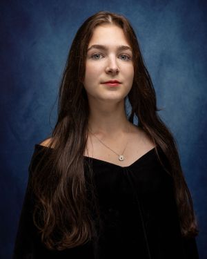 A portrait against a dark blue backdrop features long dark hair and a black velvet top.