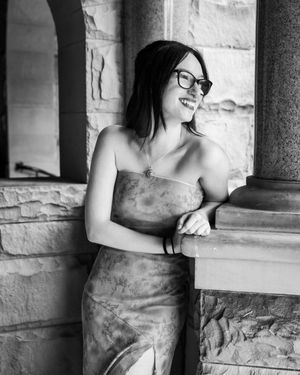 Black and white portrait session against stone wall with architectural columns.