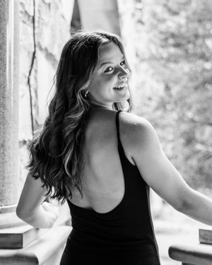 Person in black tank top poses joyfully in black and white portrait.