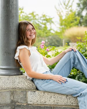 A person in casual attire relaxes on stone steps near blooming flowers.