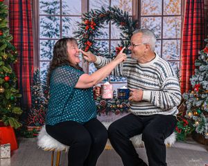 Couple sharing a playful moment together in front of a festive Christmas holiday backdrop.